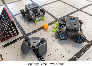 Two robots navigate a grid on the table, engaging in a fun activity with a controller nearby.