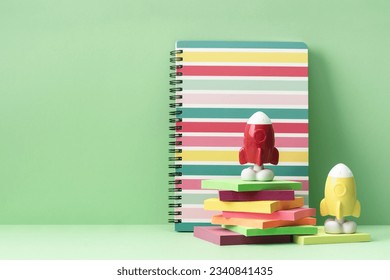 Two Rockets notebook and pile of note pads on green background. Back to School and creativity concept. Copy space. Success and achievement. teamwork