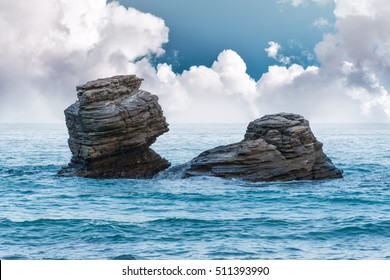 Two rocks isolated in the sea with dramatic clouds above