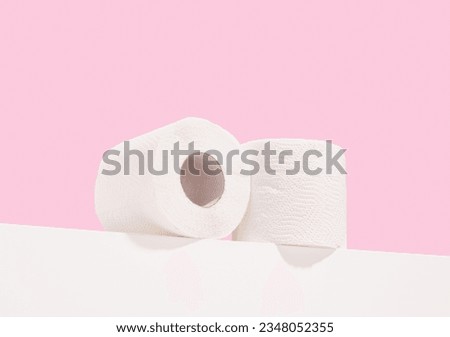 Two rolls of white toilet paper lay on the table. Personal hygiene and body care.