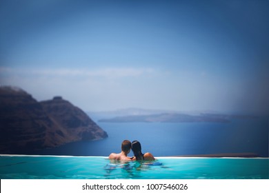 two in a romantic journey. Lovers swim in the pool overlooking the sea. Blue water and sky. View of the mountains and volcano islands - Powered by Shutterstock