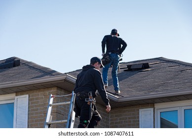 Two roofers inspecting a damaged roof