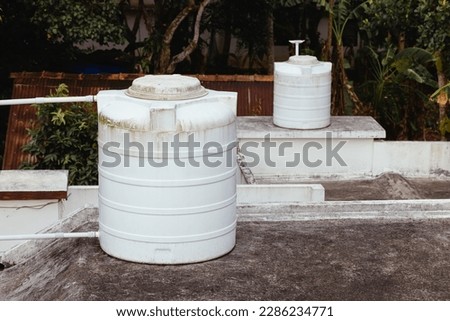 Two rooftop tanks for collecting and using water in a residential building in Southeast Asia. Water tanks on the roof are a great way to conserve water. A pump lifts water into the tank, which can the