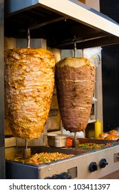 Two rotating skewered chicken and lamb meat grilled in stainless steel grill and ready to serve in a typical Middle Eastern fast food kebab sandwich