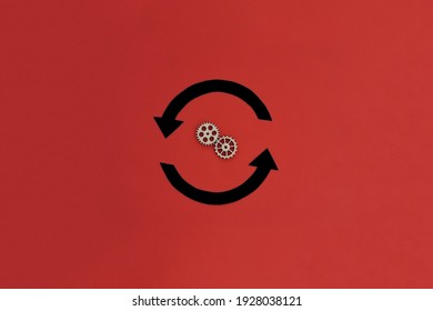 Two Round Black Arrows, Two Wooden Gears On A Red Background. Action, Movement.