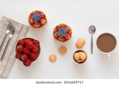 Two round no bake strawberry mini cheesecakes with salt caramel and halfs of strawberries, embellished with real blue blossoms.
White wooden table. Top down view. - Powered by Shutterstock