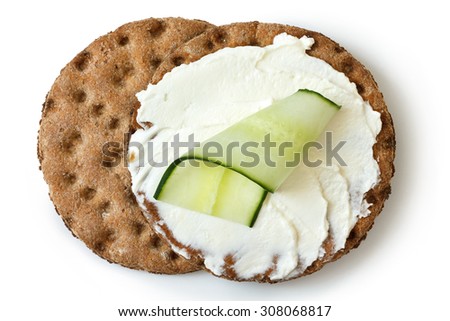 Two round rye crispbread isolated on white from above. Spread with cream cheese and cucumber slice.