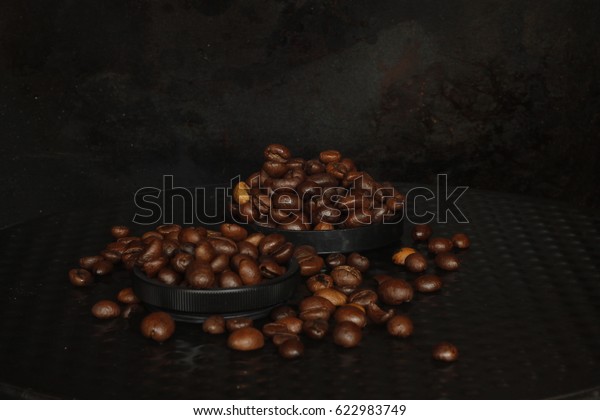Two round small shapes with roasted coffee beans in\
the dark