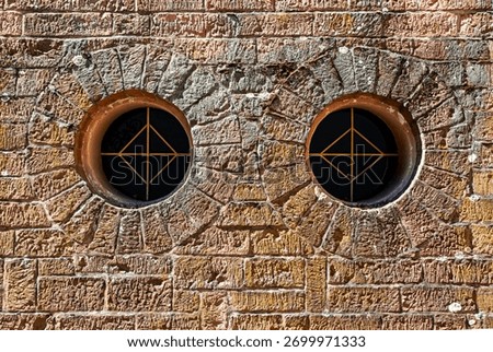 Two round windows in a stone wall
