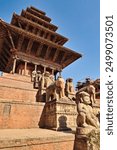 Two rows of big stone statues, sculptures, guardians line up next to the stairs leading up to the Nyatapola Temple with its elaborate wooden roof construction, Bhaktapur, Nepal 2022