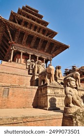 Two rows of big stone statues, sculptures, guardians line up next to the stairs leading up to the Nyatapola Temple with its elaborate wooden roof construction, Bhaktapur, Nepal 2022