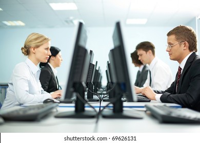 Two Rows Of Businesspeople Working On Computers