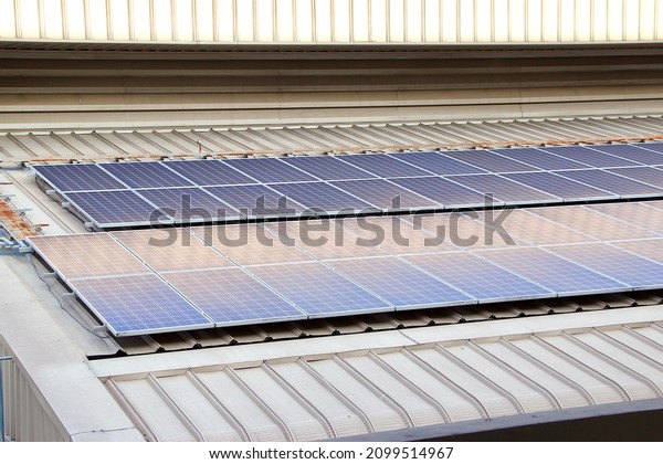 Two rows of Photovoltaic
solar cell roof top on top of the indoor car parks building in
Thailand, under renewable green energy or engery transition work or
project 
