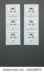 Two rows of three white power sockets with frame on dark grey wall as a background. Minimalism concept