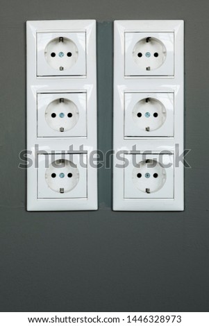 Two rows of three white power sockets with frame on dark grey wall as a background. Minimalism concept