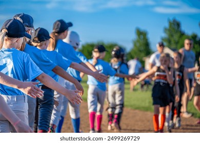 Two rows of youth girl softball players after a game giving high-fives - Powered by Shutterstock