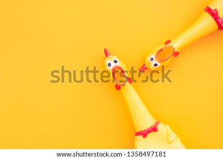 Two Rubber Chicken Toys on a yellow Background and Copyspace. Screaming rubber chicken toy on orange background
