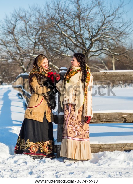 2人のロシア人ボイヤーが 冬の終わりに 柵の近くの村でロシアの民族衣装を着た の写真素材 今すぐ編集