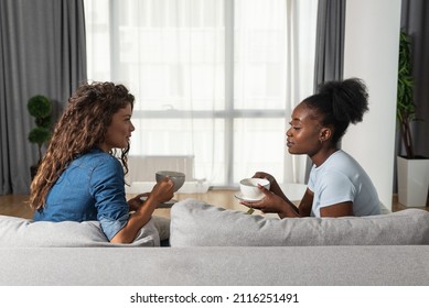Two sad depressed and anxious diverse women talking at home. Female friends supporting each other while they drinking coffee or tea. Problems, friendship and relationships difficulties care concept