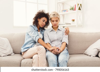 Two Sad Diverse Women Talking At Home. Female Friends Supporting Each Other. Problems, Friendship And Care Concept