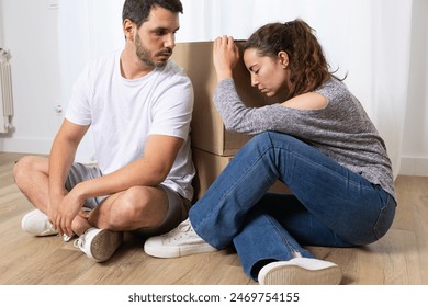 Two sad evicted tenants moving home with belongings sitting on the floor. Exhausted couple after finishing the move - Powered by Shutterstock