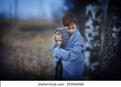 Two Sad Little Embracing Children In The Field On A Cool Spring Evening. Kids In The Country