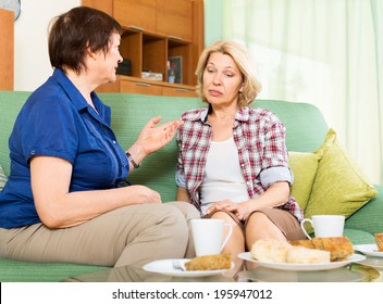 Two Sad Mature Women Talking On Couch At Home