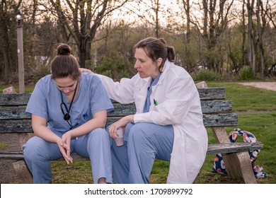 Two Sad Nurses In Scrubs Taking A Break Outside On A Spring Evening. Overworked Healthcare Workers Concept.