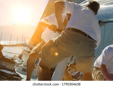 Two Sailing Crew Members Working Rigging On Sail Boat With Lens Fare