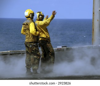 Two Sailors Intently Taxi A Waiting Aircraft On To A Waiting Catapult Onboard An Aircraft Carrier