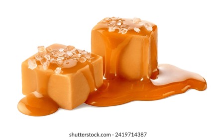 Two salty caramel candy cubes topped with caramel sauce and salt isolated on white background