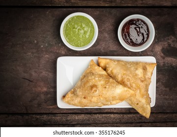 Two Samosas Served With Mint Coriander Chutney And Tamarind Chutney