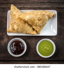 Two Samosas With Tamarind Chutney And Mint Sauce