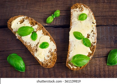 Two Sandwiches Of Rye Bread With Butter And Basil. Top View.