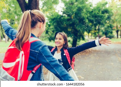 Two School Friends Hugging, Meet In The Park. Walking Into Each Other With Open Arms And Smiling. The Concept Of School, Study, Education, Friendship, Childhood