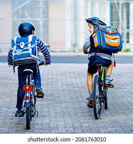 Two School Kid Boys In Safety Helmet Riding With Bike In The City With Backpacks. Happy Children In Colorful Clothes Biking On Bicycles On Way To School. Safe Way For Kids Outdoors To School