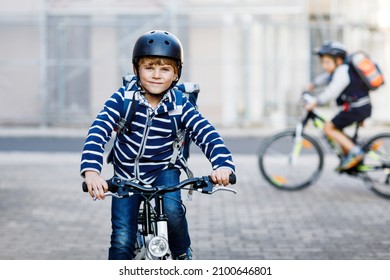 Two school kid boys in safety helmet riding with bike in the city with backpacks. Happy children in colorful clothes biking on bicycles on way to school. Safe way for kids outdoors to school - Powered by Shutterstock