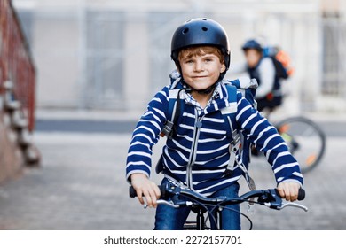 Two school kid boys in safety helmet riding with bike in the city with backpacks. Happy children in colorful clothes biking on bicycles on way to school. Safe way for kids outdoors to school - Powered by Shutterstock