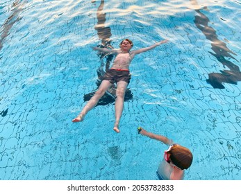 Two School Kids Boys Playing And Splashing In An Outdoor Swimming Pool On Warm Summer Day. Happy Healthy Children Enjoying Sunny Weather In City Public Pool. Kids Activity Outdoors With Water.