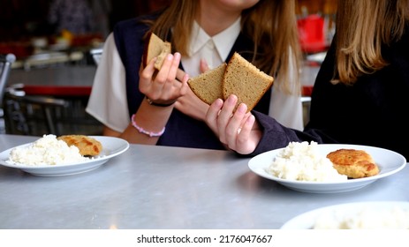 Two schoolgirl girls are sitting in the school cafeteria and are going to have lunch. School food concept - Shutterstock ID 2176047667