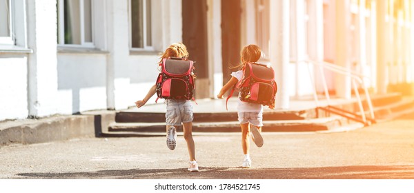 Two Schoolgirls Holding Each Other's Hands Run To School, Back To School, Primary Education Of Children.