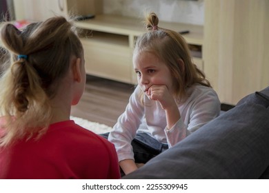 Two schoolgirls sit on the sofa in the living room and discuss misunderstandings, difficulties and family problems. The concept of help and compassion within the family - Shutterstock ID 2255309945