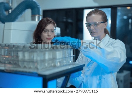Two scientist testing water quality sample for microplastics and chemical contaminants in laboratory.