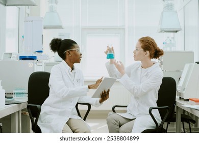 Two scientists discussing an experiment while holding a tablet and beaker in a bright laboratory with advanced equipment present, highlighting teamwork and scientific research
