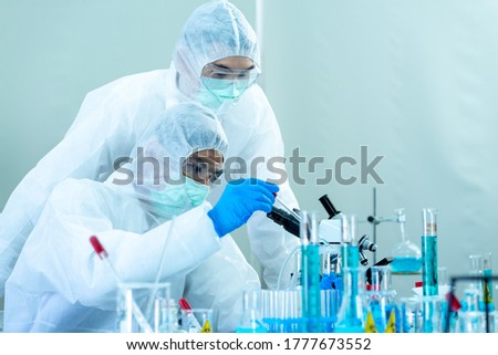 two scientists testing blood sample from test tube galssware with microscope in science laboratory equipment to diagnosis for virus pandemic
