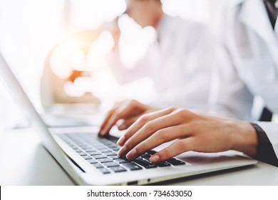 Two scientists are working in laboratory. Cropped image of young female researcher and her senior supervisor are doing investigations with microscope and laptop. - Powered by Shutterstock