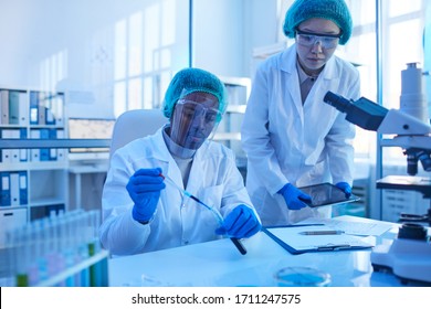 Two scientists working in team at the table they examining samples in test tubes