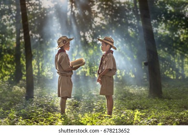 Two Scouts Are Reading A Book Scout Promise And Law In The Woods.