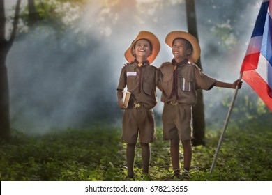 Two Scouts Are Reading A Book Scout Promise And Law In The Woods.