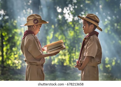 Two Scouts Are Reading A Book Scout Promise And Law In The Woods.